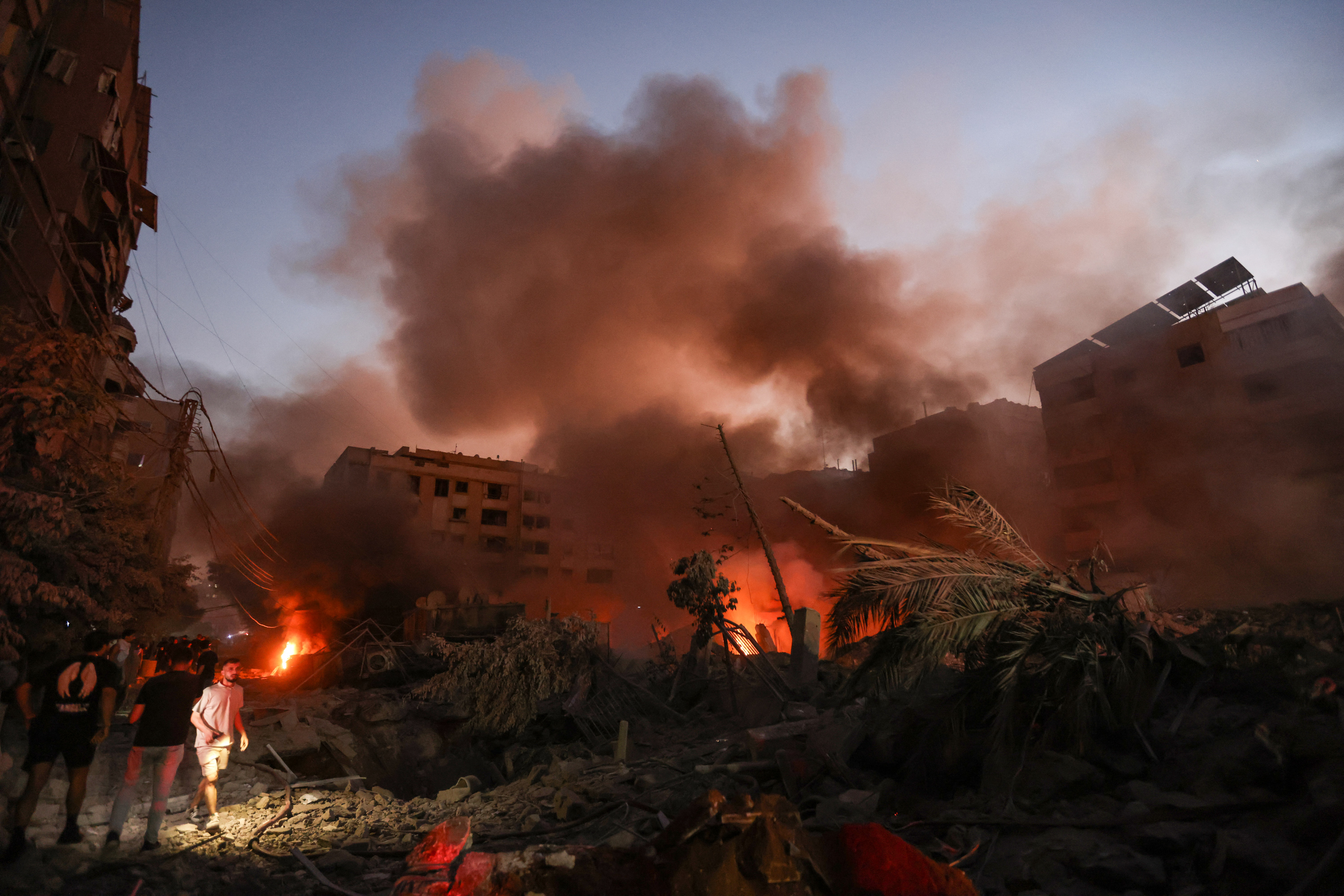 Smoke rises from the smouldering rubble as people gather at the scene of Israeli air strikes in the Haret Hreik neighbourhood of Beirut's southern suburbs on September 27, 2024. A source close to Hezbollah said the massive Israeli strikes on Beirut's southern suburbs flattened six buildings. (Photo by Ibrahim AMRO / AFP) (Photo by IBRAHIM AMRO/AFP via Getty Images)