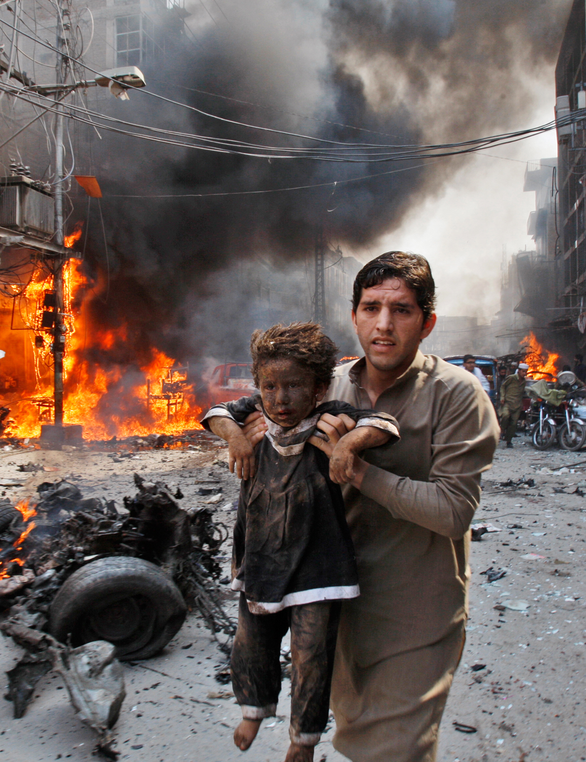 A Pakistani man carrying a child rushes away from the site of a blast shortly after a car bomb exploded in Peshawar, Pakistan, Sunday, Sept. 29, 2013. A deadly car bomb exploded on a crowded street in northwestern Pakistan Sunday, in the third blast to hit the troubled city of Peshawar in a week, officials said. (AP Photo/Mohammad Sajjad)